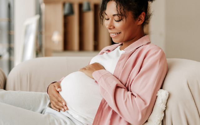 A pregnant mother holds her stomach and smiles