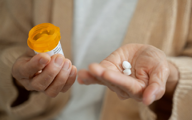 A woman holds pills and a pill bottle
